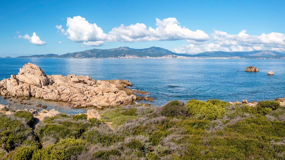 A coastal landscape with rocky formations and clear blue waters.
