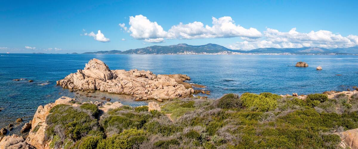 A coastal landscape with rocky formations and clear blue waters.