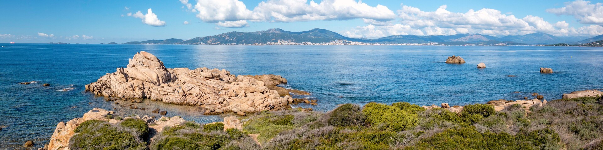 A coastal landscape with rocky formations and clear blue waters.