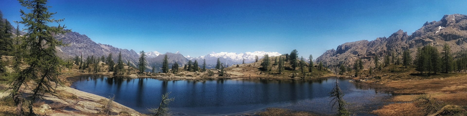 A mountain lake surrounded by evergreen trees and snow-capped peaks.