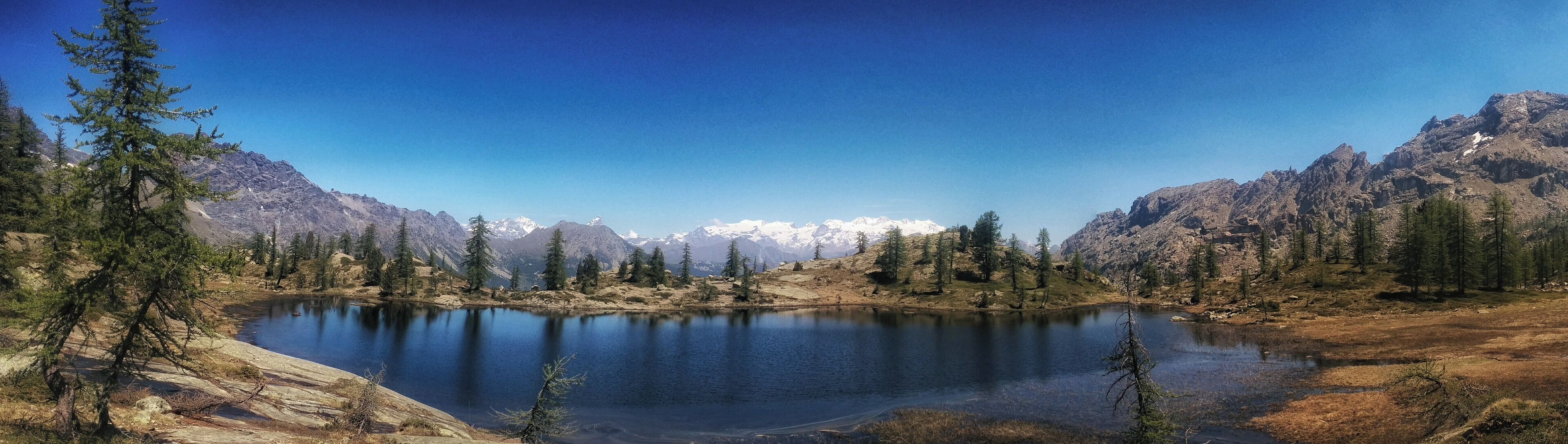 A mountain lake surrounded by evergreen trees and snow-capped peaks.