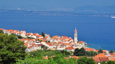 A coastal town with red-roofed buildings, a prominent clock tower, and a clear view of the sea.