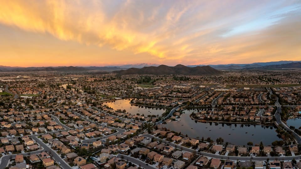 A cityscape with residential areas, a large lake, and mountains in the background.