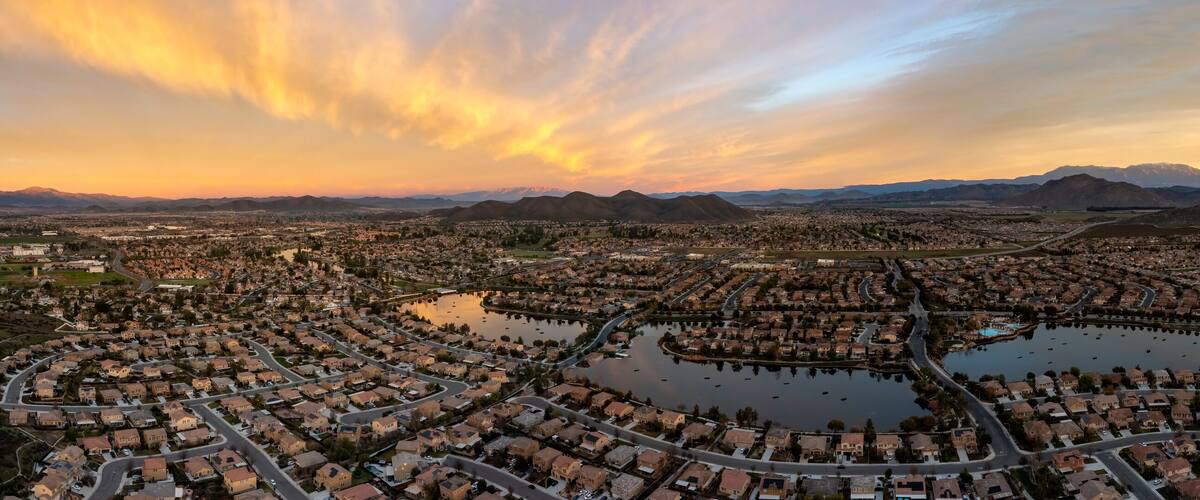 A cityscape with residential areas, a large lake, and mountains in the background.