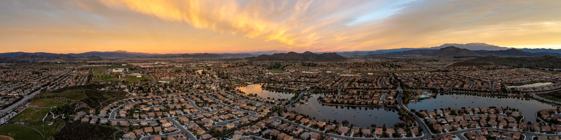 A cityscape with residential areas, a large lake, and mountains in the background.