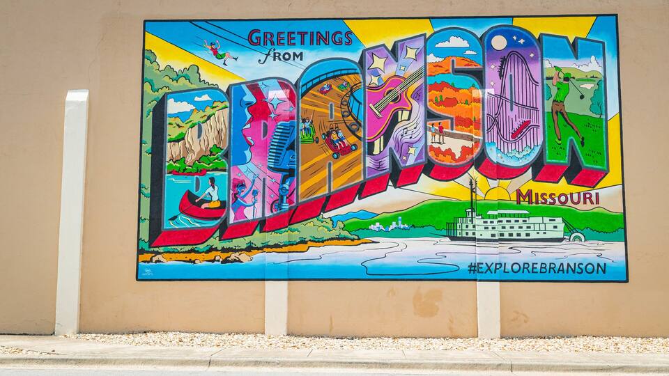 Une fresque colorée sur laquelle on peut voir le mot « BONJOUR » ainsi que diverses activités, comme le kayak, le golf et une vue sur la ville.