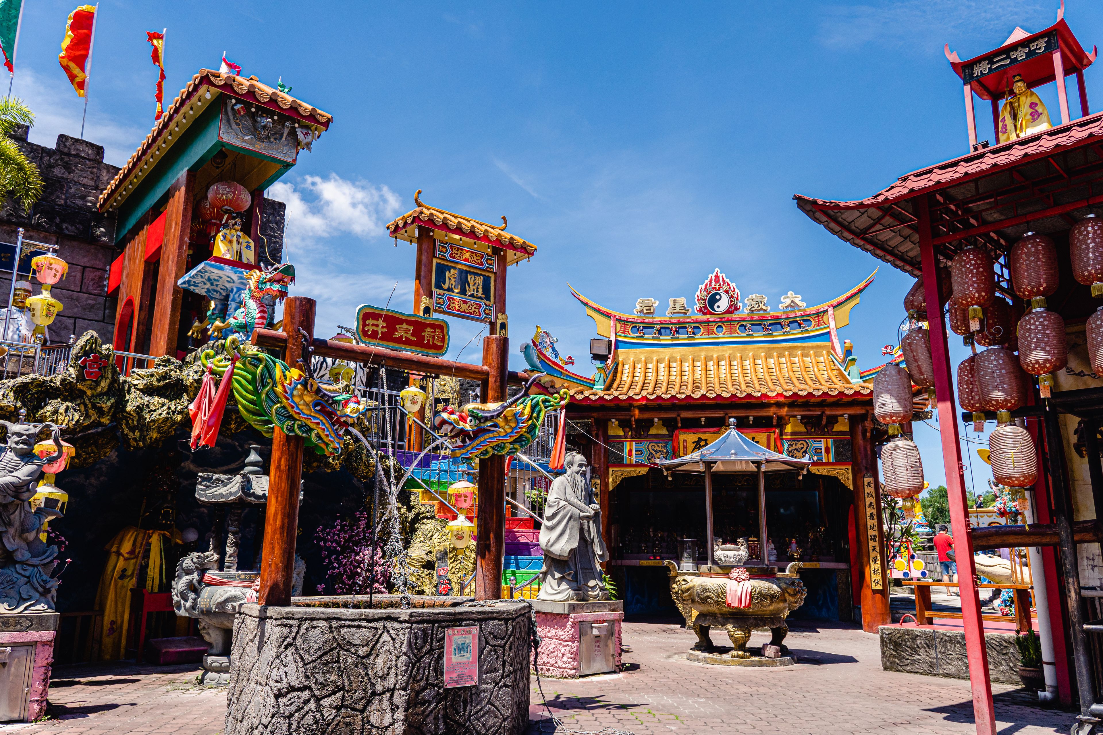 A traditional Chinese temple with ornate architecture, including a dragon statue and a large lion statue.