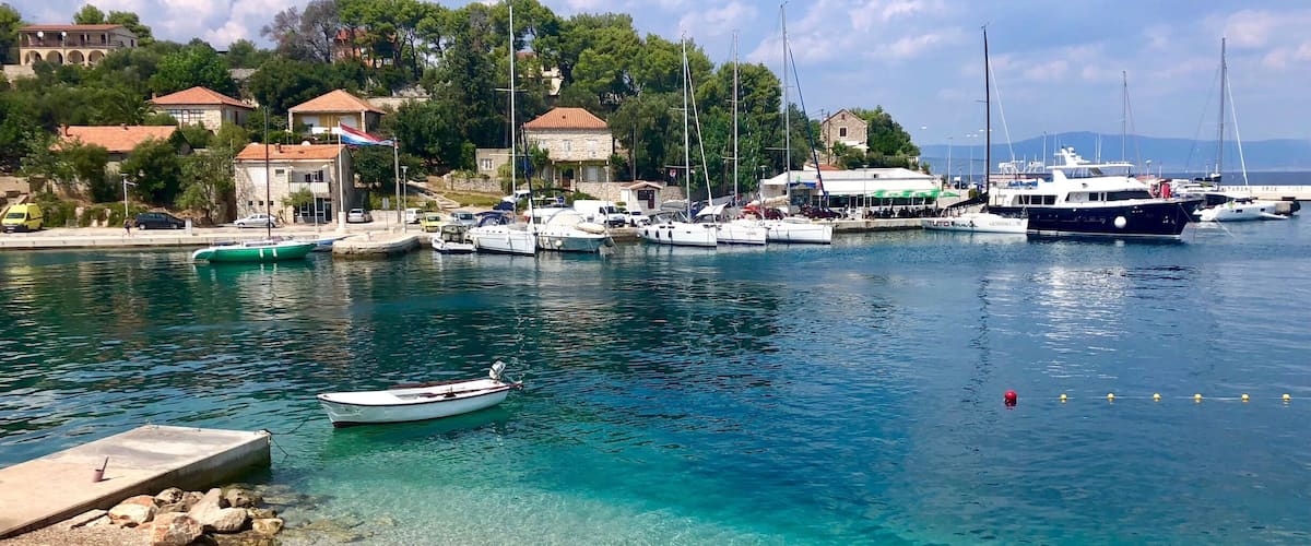 A marina with boats, a clear beach, and buildings in the background.