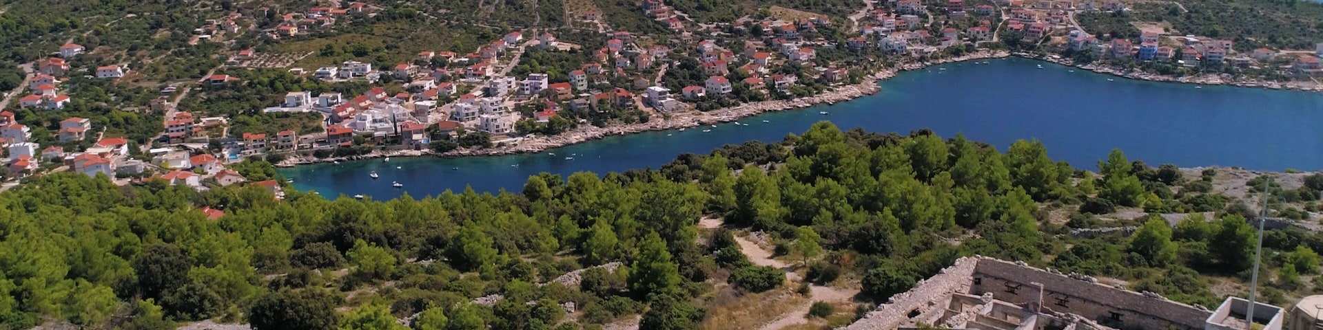 Mediterranean coast, C4k aerial, drone shot, bypassing old ruins, on the top of a hill, overlooking small razanj town and the croatian shore, at the adriatic sea, on a summer day, in Croatia