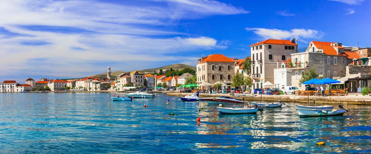 Kastel Novi 10k panorama of traditional Dalmatian village with orange roofs and white stone houses in Croatia. Scenic Adriatic sea view with fishing boats in quiet water. Kastela travel scenery
