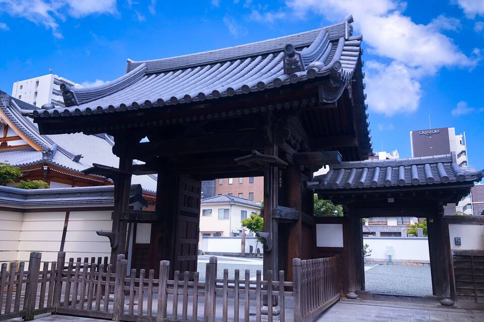 Um portão tradicional japonês, com pilares de madeira ricamente decorados e telhado em telhas.
