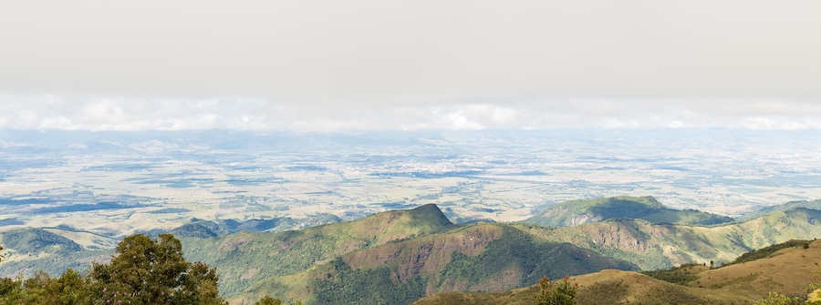 Vista panorâmica de uma paisagem montanhosa com colinas ondulantes e um vale abaixo.
