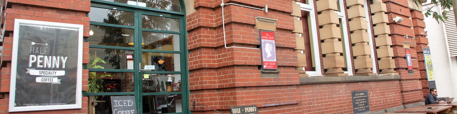 Un edificio de ladrillo con una gran entrada en arco y un letrero que dice 'Half Penny Specialty Coffee'.