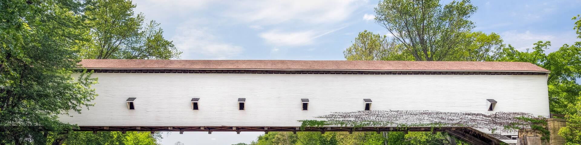 The white single span Jackson Covered Bridge crosses Sugar Creek in rural Parke County, Indiana