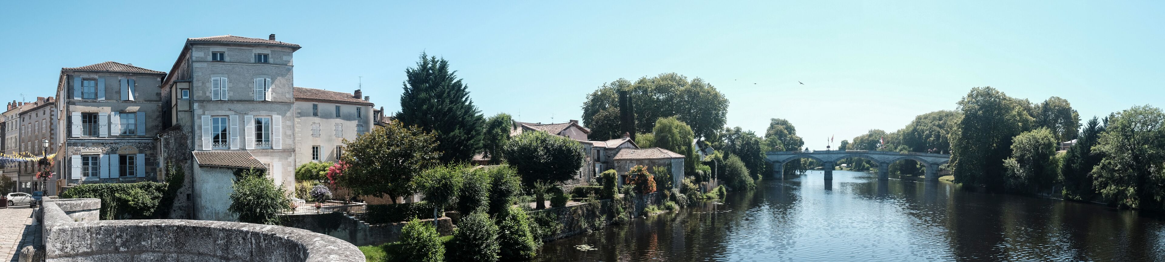 A river with a stone bridge, historic buildings, and trees along the banks.