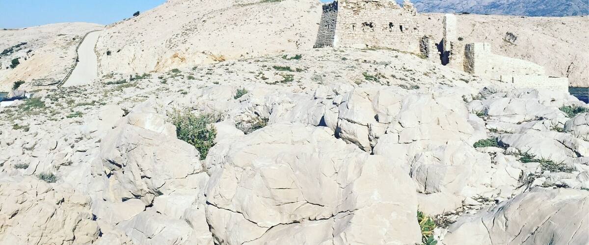 A rocky landscape with ancient ruins and a clear blue sky.