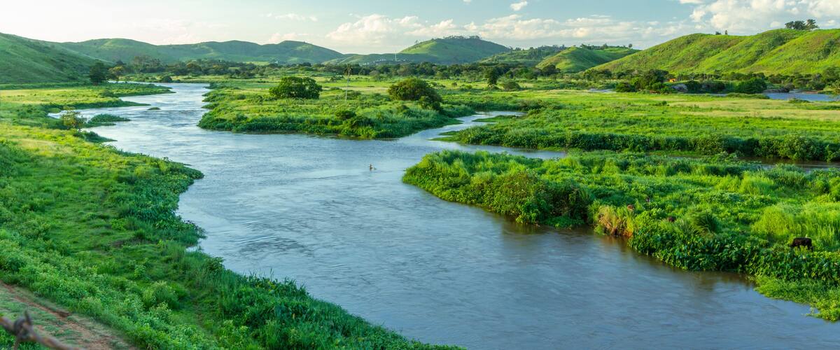 A river winding through lush green fields and hills.