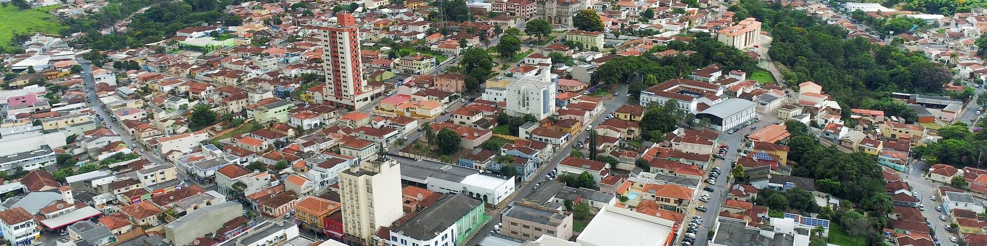A densely populated urban area with a prominent church, a tall building, and surrounding green hills.