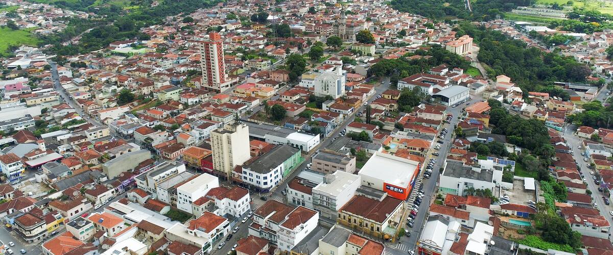 A densely populated urban area with a prominent church, a tall building, and surrounding green hills.