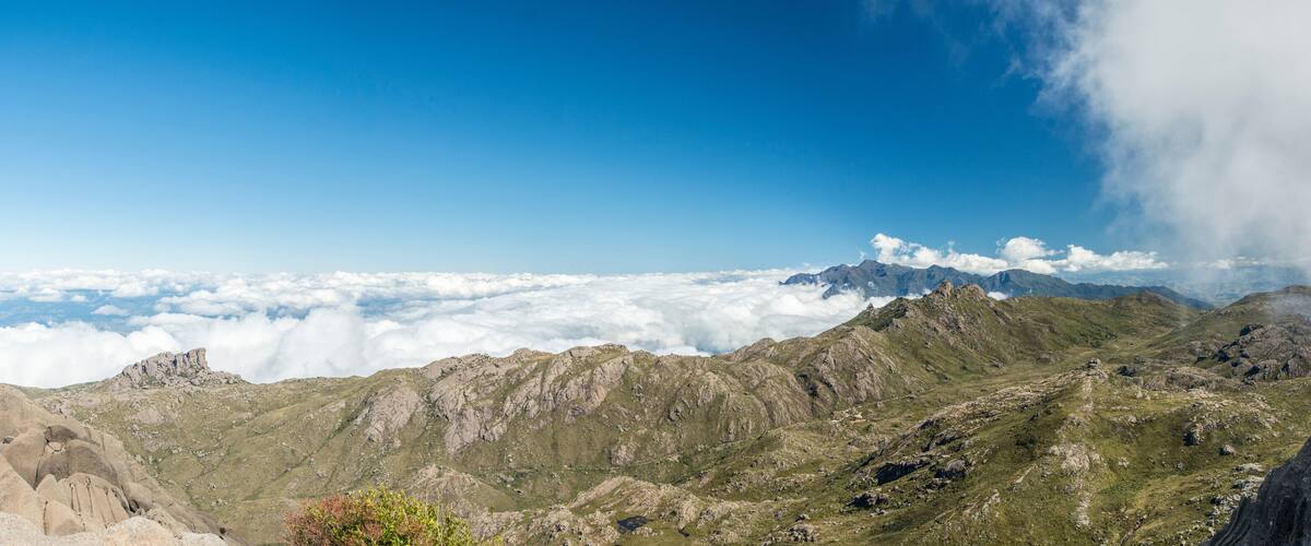 A mountain landscape with rocky terrain and a view of clouds below.