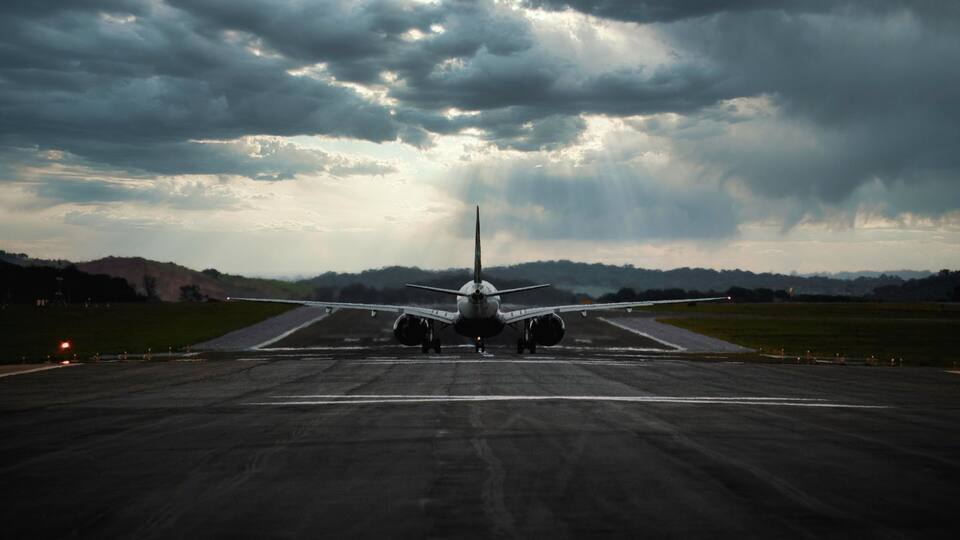 An airplane on a runway with a cloudy sky in the background.