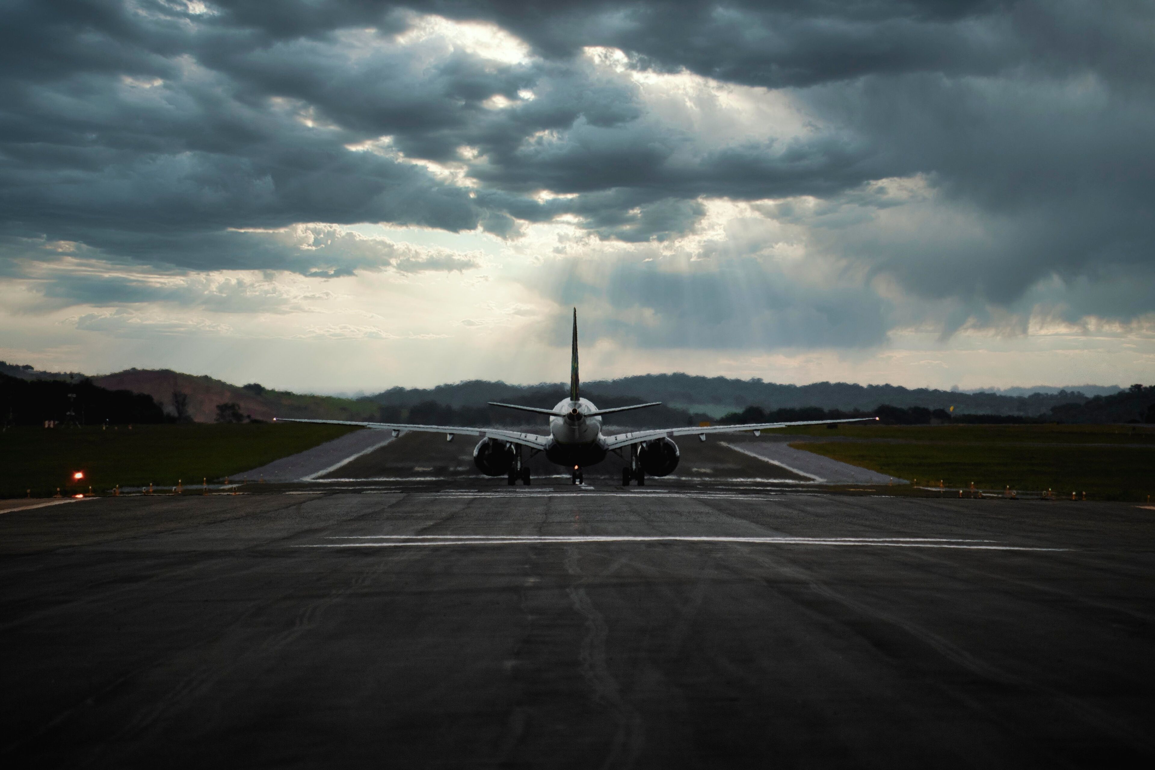 An airplane on a runway with a cloudy sky in the background.