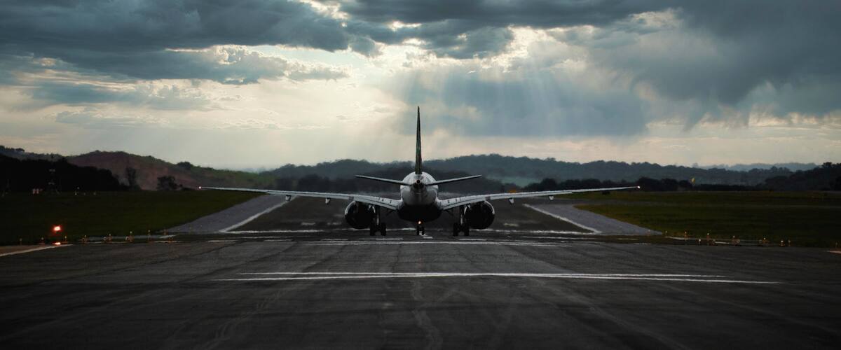 An airplane on a runway with a cloudy sky in the background.