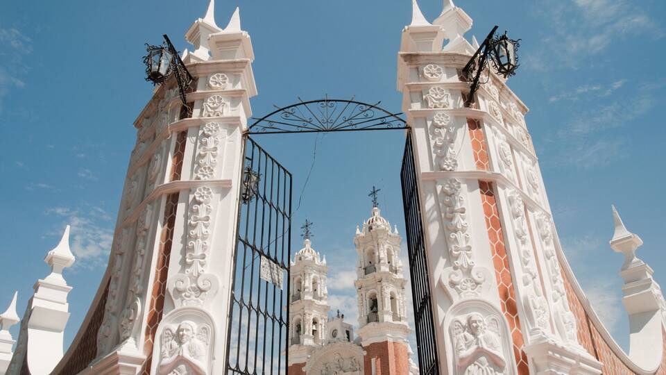 A white church with ornate architecture and a metal gate.