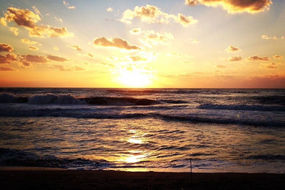 A sunset over the ocean with waves and a clear sky.