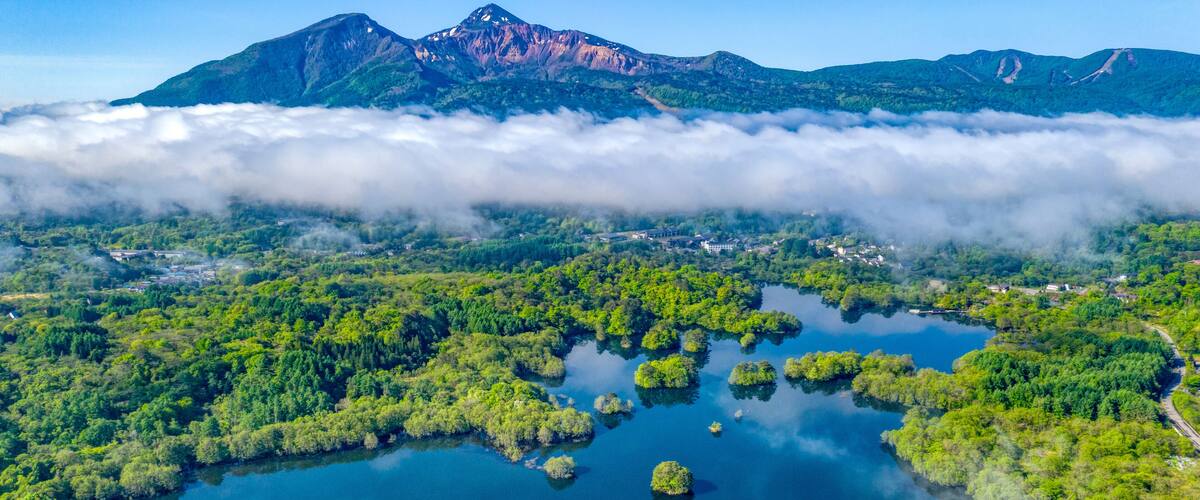 A mountainous landscape with a lake surrounded by dense forest and a village.