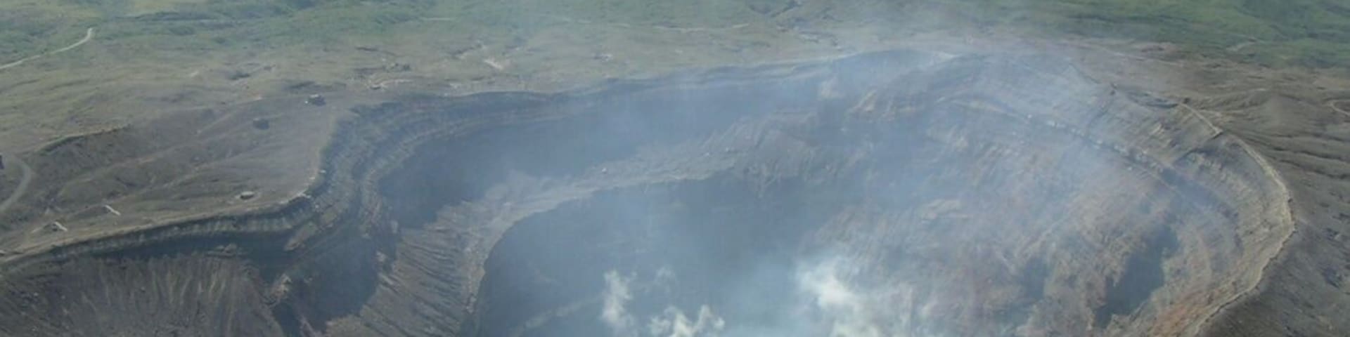 Mount Aso acid lake (crater of Mount Naka) seen from helicopter. Green mountains in the background, in the NW direction, are Mounts Kijima (left) and Ojo (right). Aso caldera walls are also visible further back. The picture points to the NW direction.