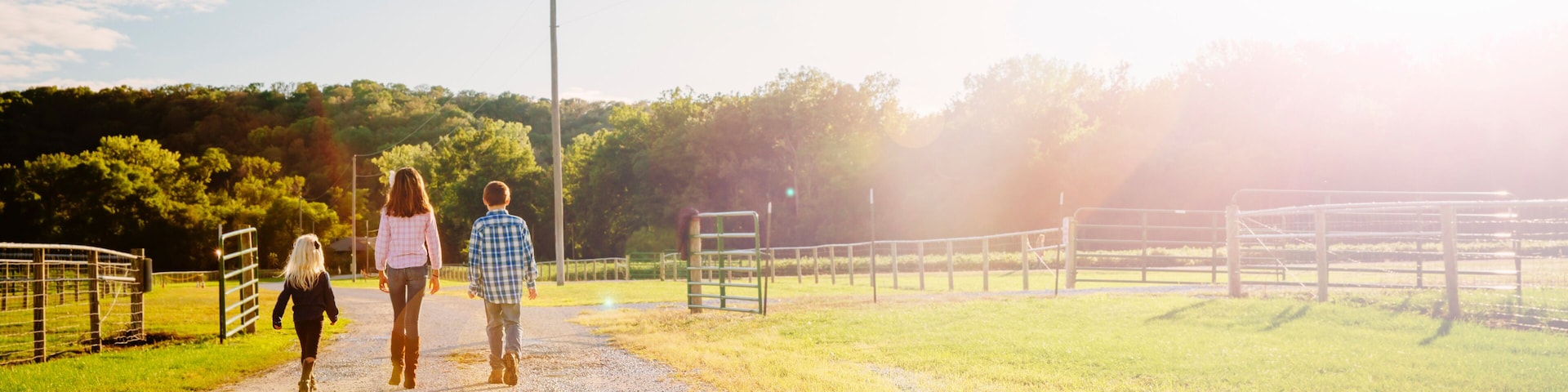 Caucasian children walking on dirt road on ranch