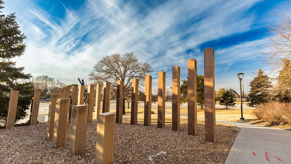 A series of tall, rectangular stone pillars in a park with a clear sky.