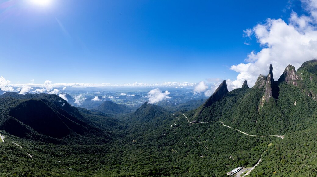 Super wide aerial panorama landscape of road meandering through postcard trail Brazilian mountain range Serra dos Orgaos in Teresopolis, Rio de Janeiro, with Soberbo viewpoint in the foreground