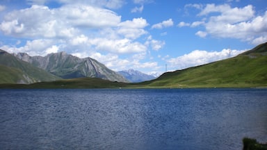 A lake surrounded by mountains under a partly cloudy sky.