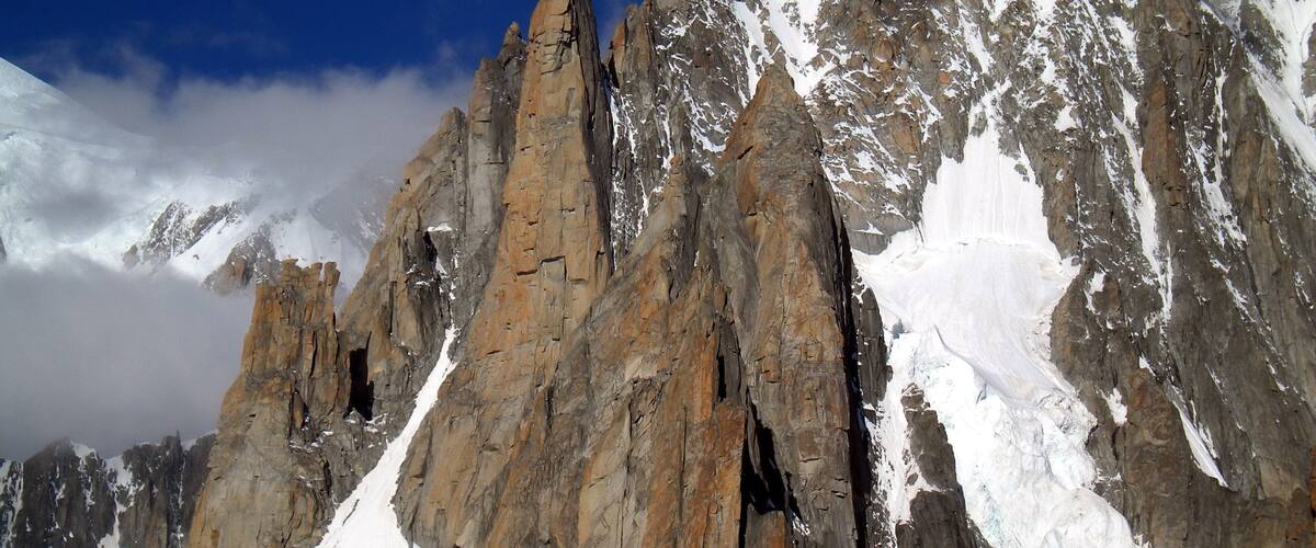 A rugged mountain range with sharp peaks and snow-covered slopes.