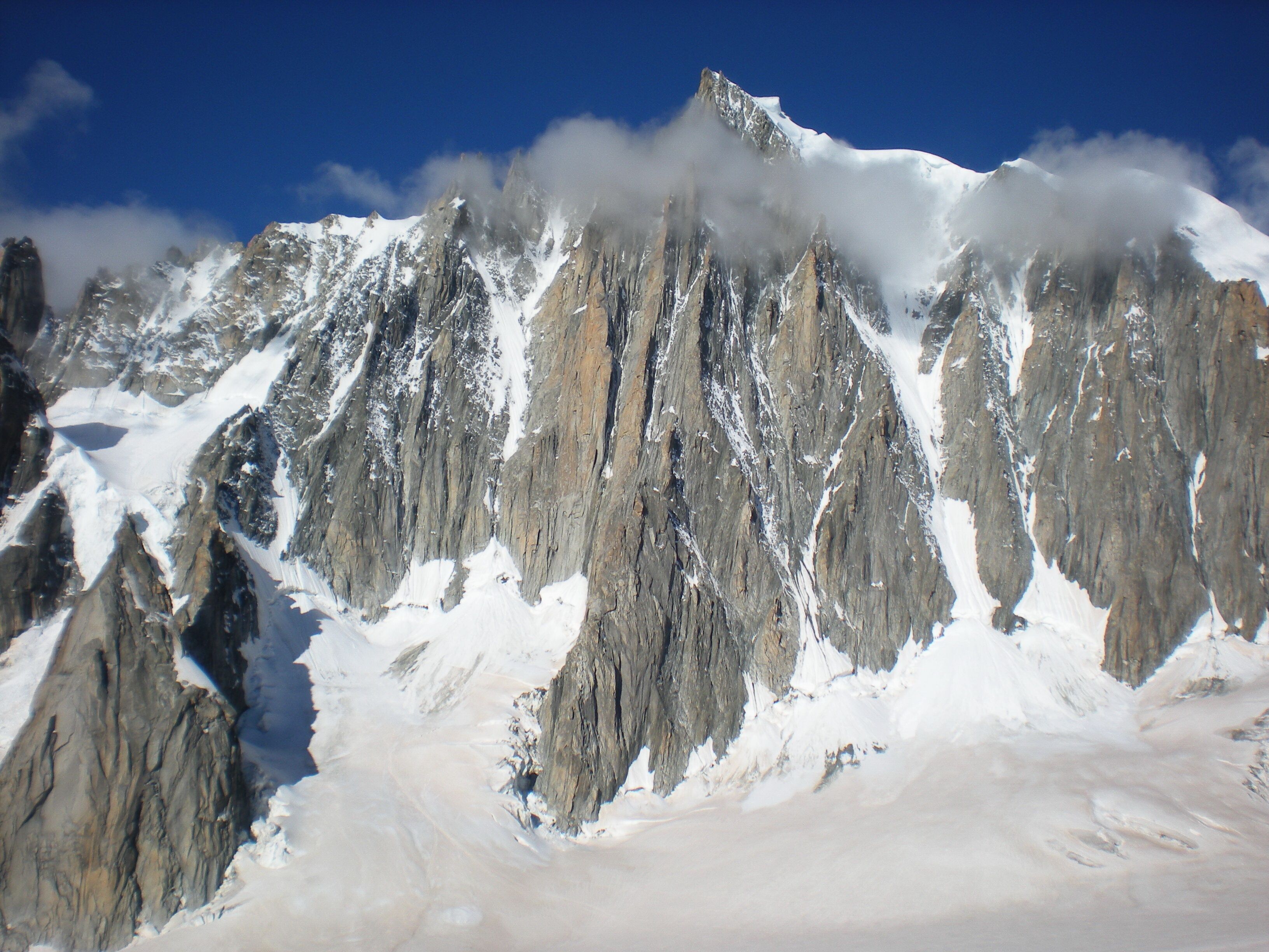Une chaîne de montagnes enneigées aux pics acérés, sous un ciel bleu et dégagé.
