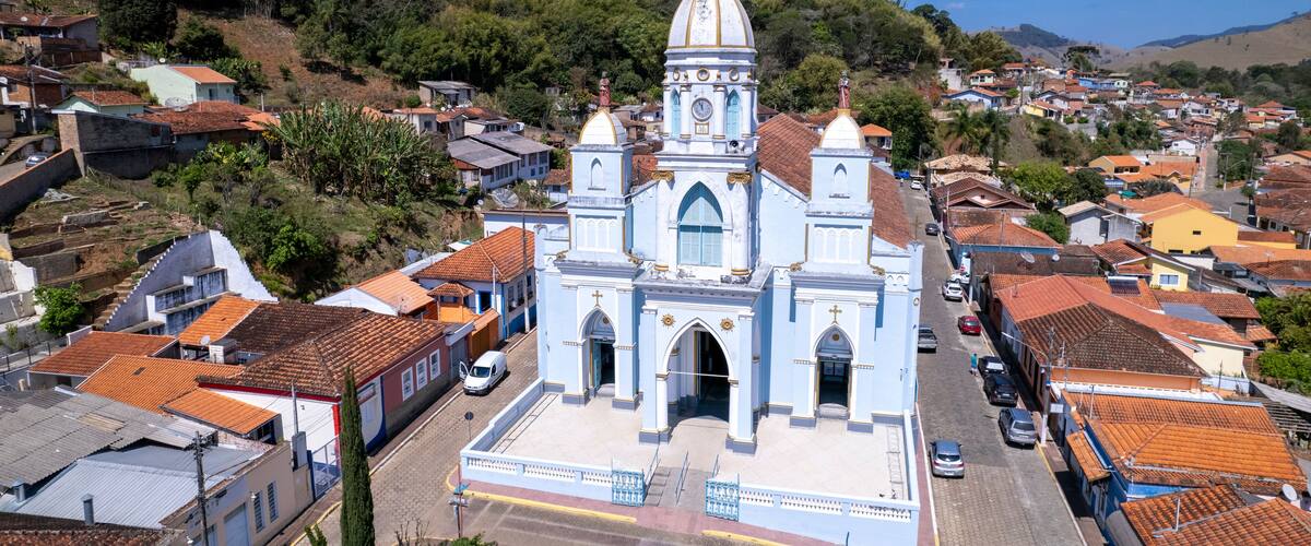 A white church with a dome and bell tower surrounded by residential buildings and hills.