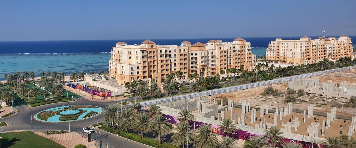 A coastal resort with high-rise buildings, palm trees, and a roundabout.