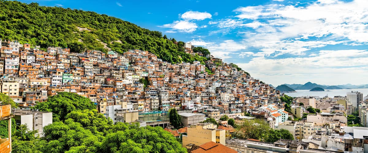 A densely packed hillside cityscape with a view of the ocean and mountains in the distance.