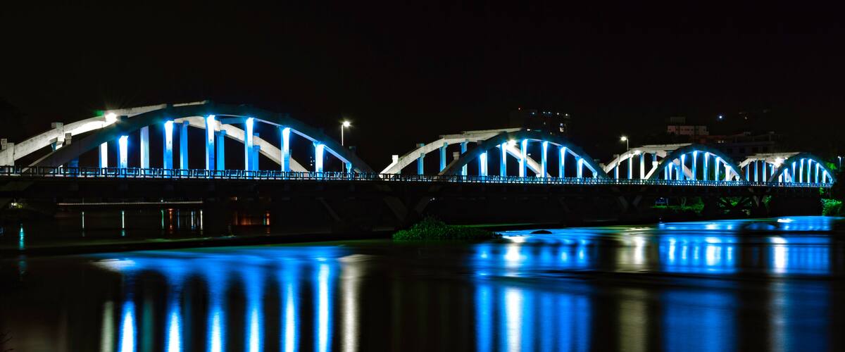 A bridge with blue lights at night, reflecting on the water.