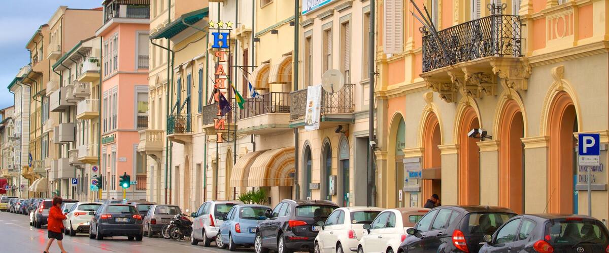 A street lined with parked cars and colorful buildings with balconies and signs.
