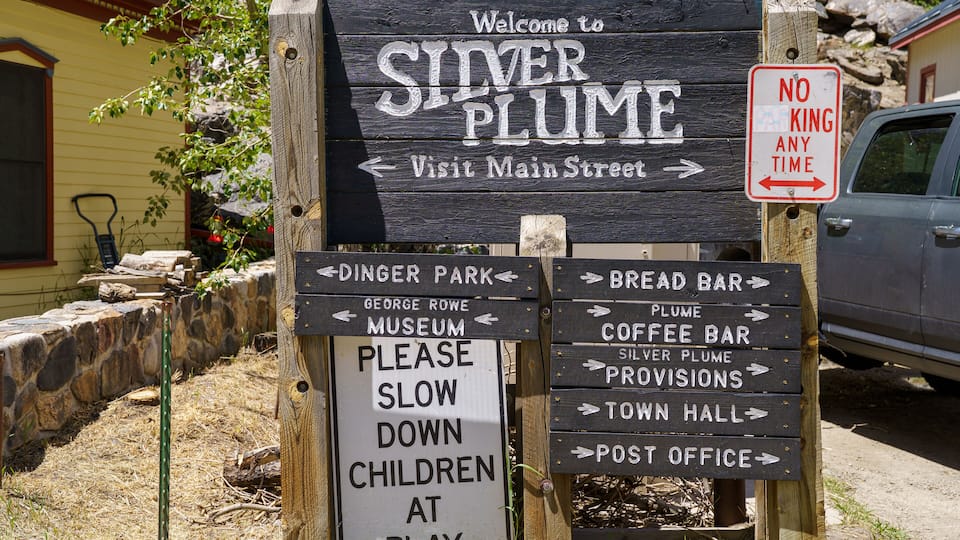 A wooden signpost with directions to Silver Plume, including a 'No Parking Any Time' sign.