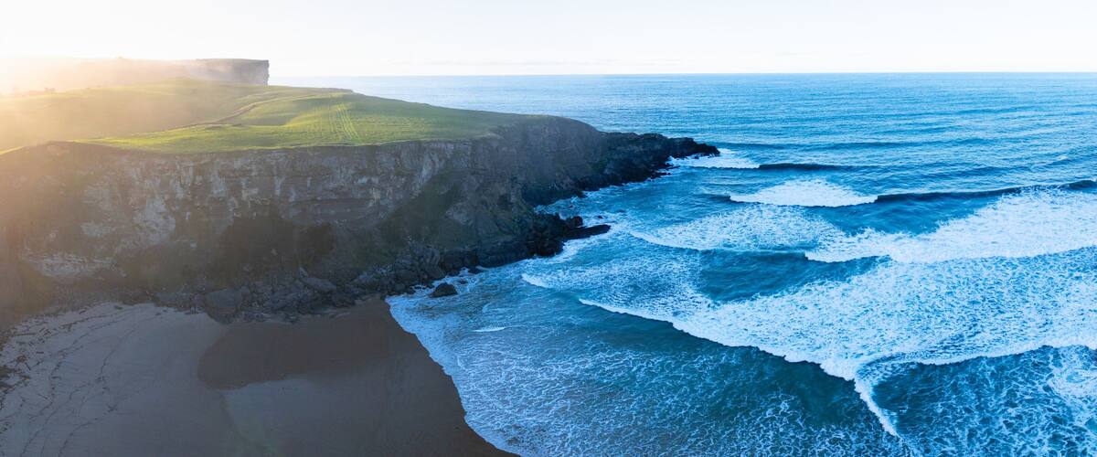 A coastal landscape with cliffs, a beach, and the ocean.