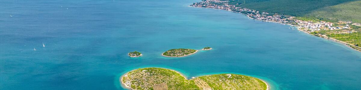 An aerial view of a coastal area with a heart-shaped island surrounded by clear blue waters.