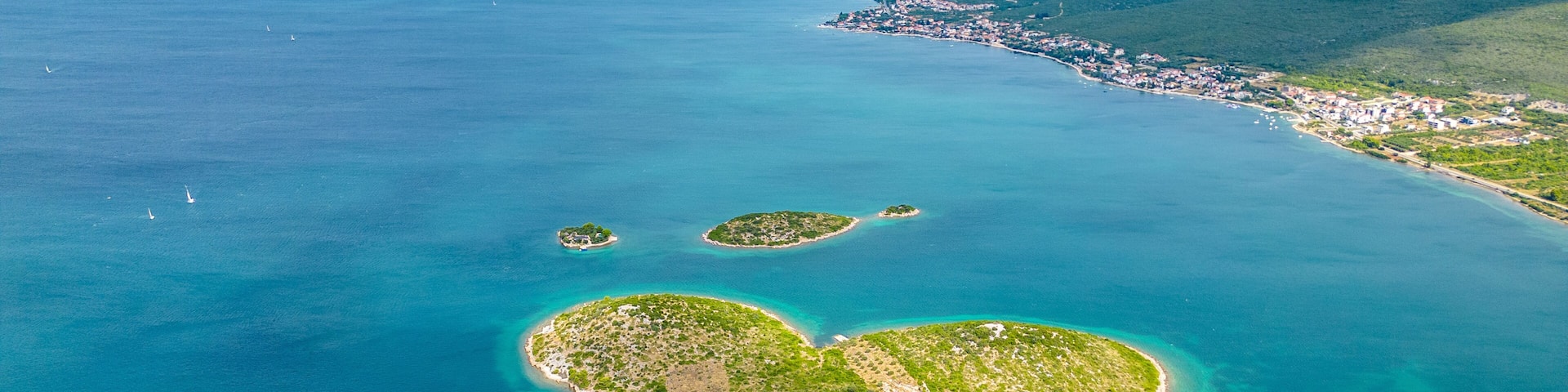An aerial view of a coastal area with a heart-shaped island surrounded by clear blue waters.