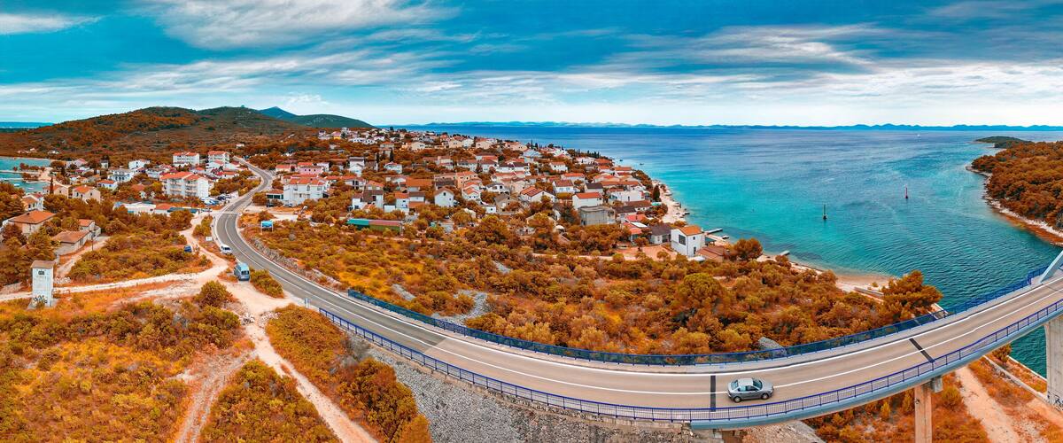 A coastal town with a bridge over water, surrounded by autumn foliage.