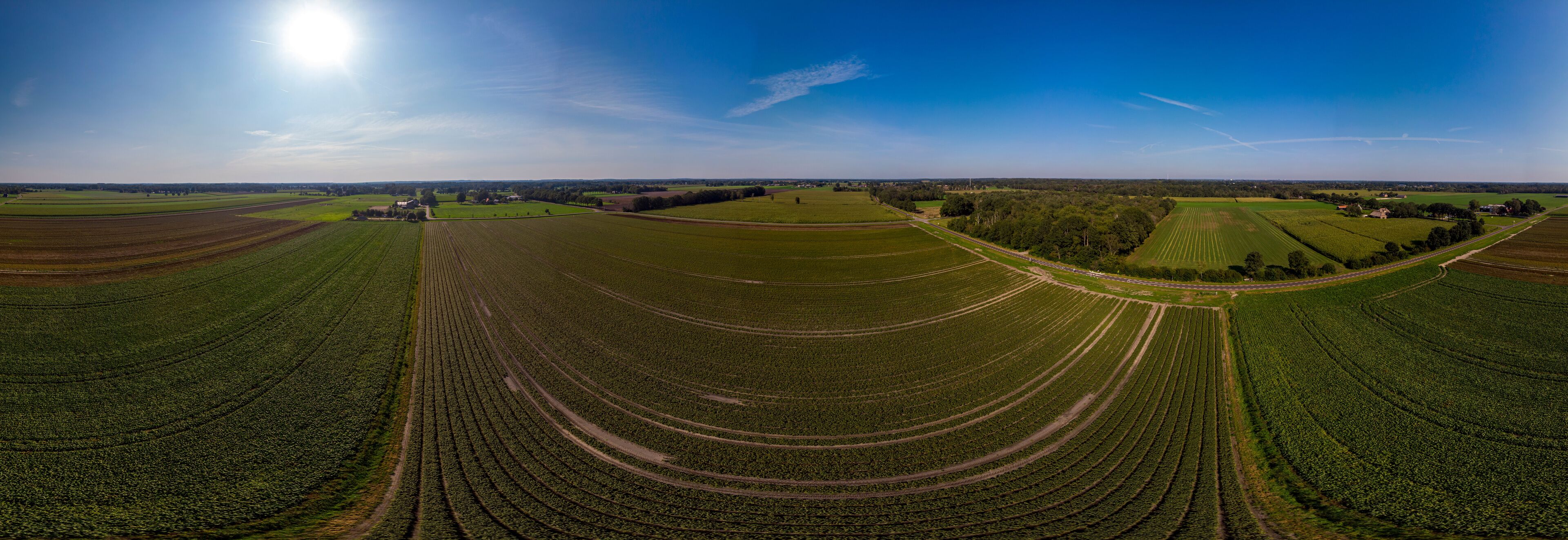 A vast agricultural landscape with terraced fields and a clear blue sky.