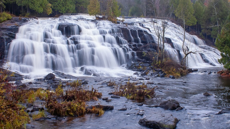A multi-tiered waterfall surrounded by autumn foliage.
