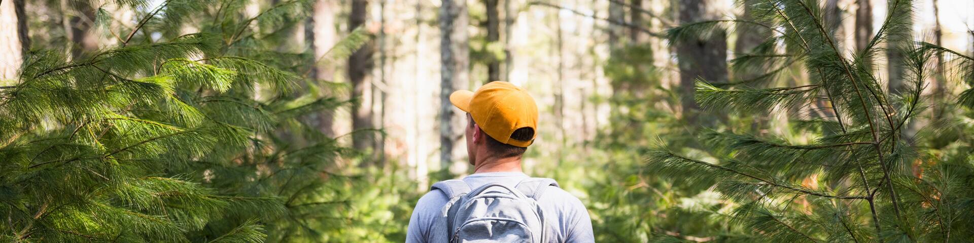Young man on nature walk with backpack and dietary supplement